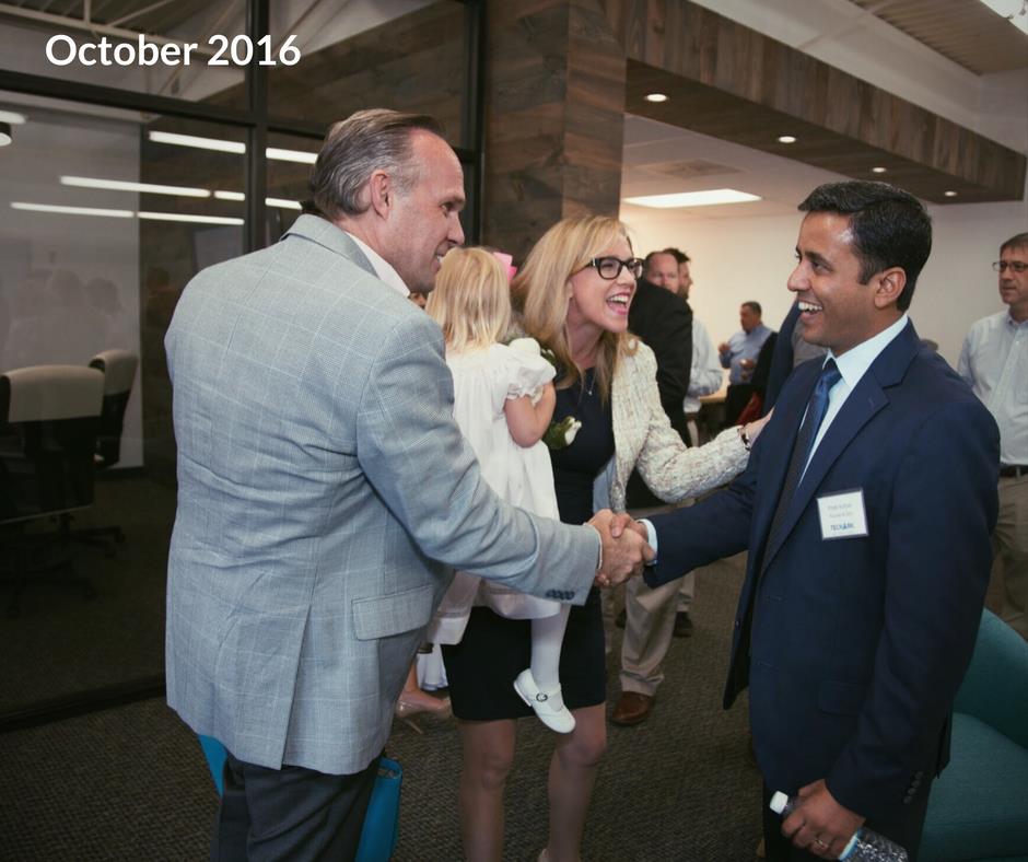 TechArk CEO shaking hands with a client and a woman holding a child