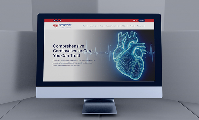 A computer monitor displaying the Birmingham Heart Clinic website featuring a digital 3D heart graphic.