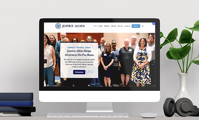 A desktop computer displaying the Justice Allies website featuring a diverse group of attorneys and a volunteer call to action.